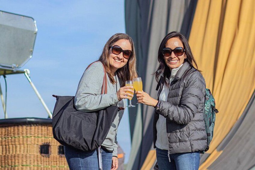 Two people holding drinks, standing in front of a large tent. 2