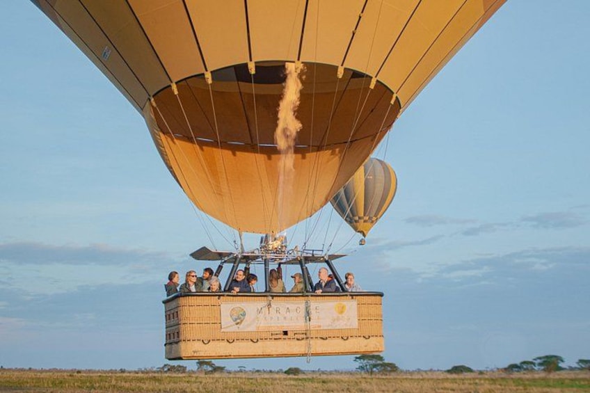 A hot air balloon with passengers, over a grassy field. 2