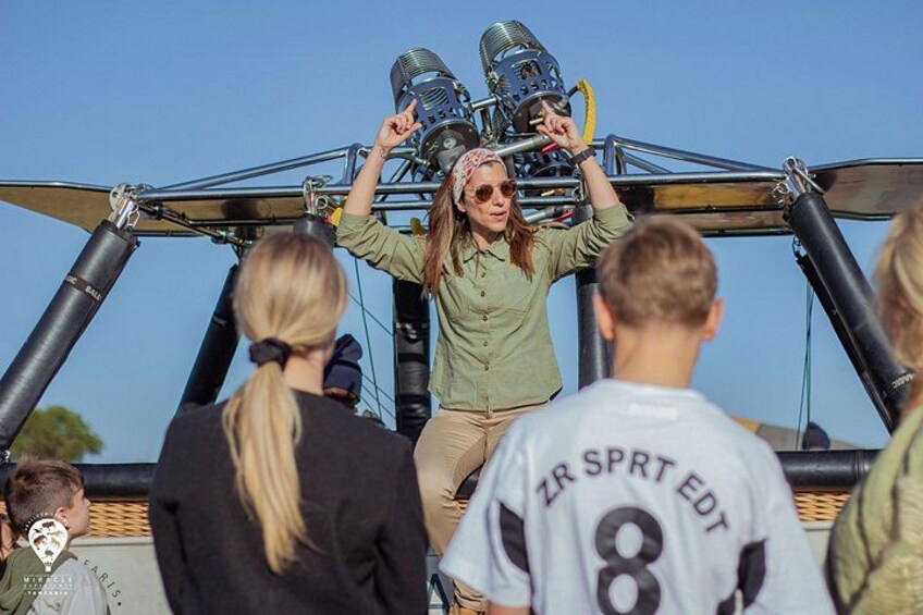 A person standing on a structure with a camera, surrounded by people. 4