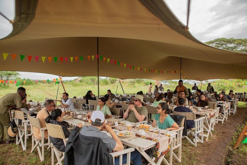 People dining under a large tent in an outdoor setting. 4