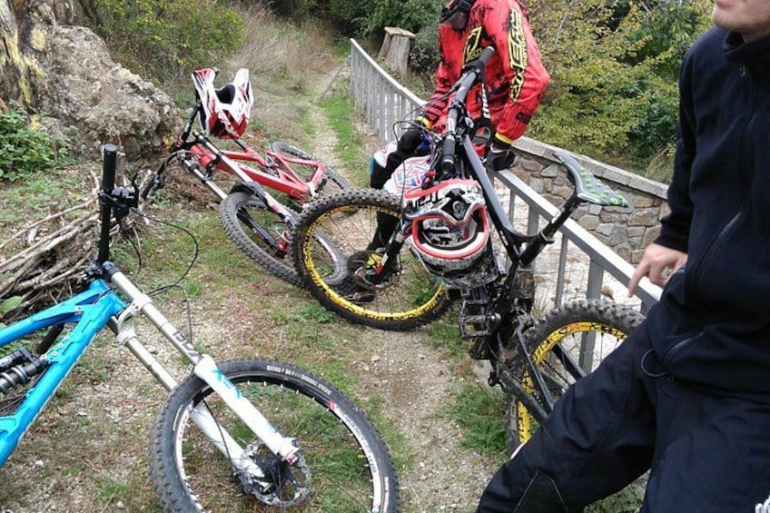 A mountain biking trail with a blue bike, a red bike, and a rider in red gear. 2