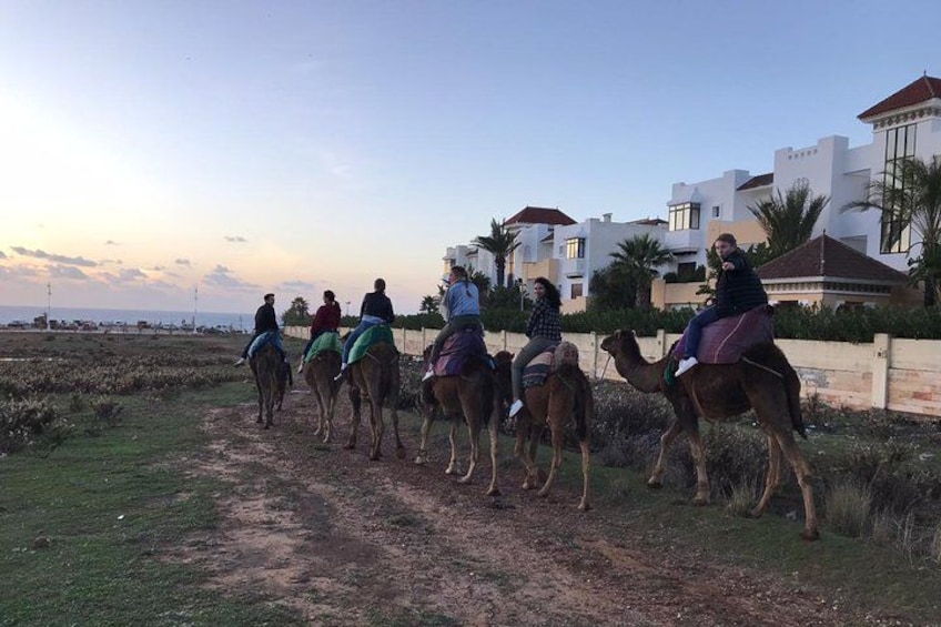 A group of people riding camels on a dirt path. 2