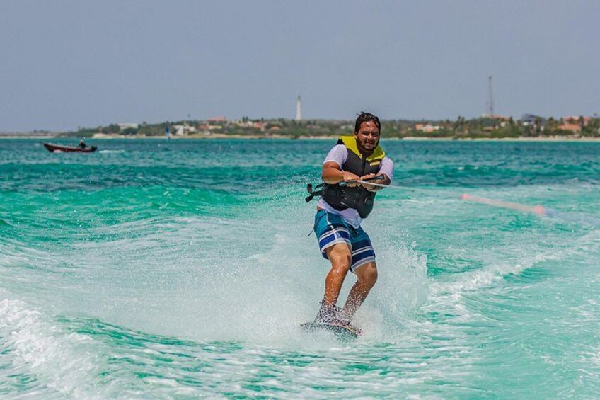 En person som åker wakeboard på turkosblått vatten med en fyr i bakgrunden. 4