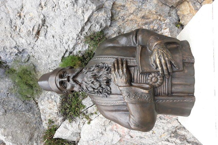 A bronze statue of a bearded man with a long beard, wearing a hat, and holding a book. 3