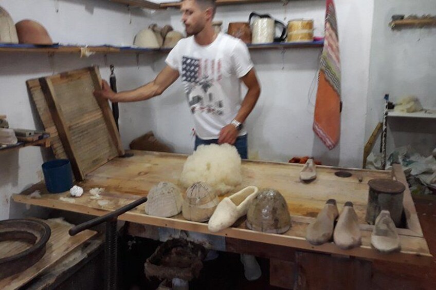 A workshop with pottery items and a person handling a wooden board. 2