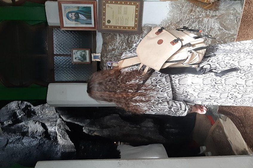 A person sitting on a bench with a backpack, surrounded by various framed items and a patterned rug. 4