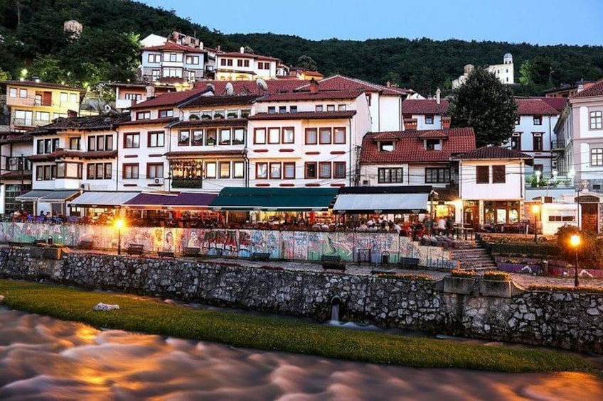 A town with historic buildings, a stone wall, and a river. 5
