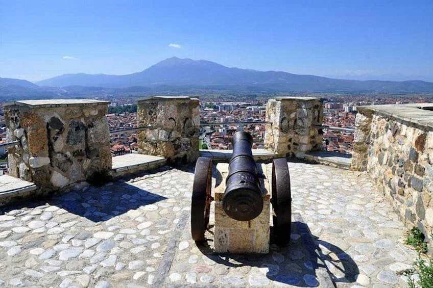 A cannon on a stone platform overlooking a city with mountains in the background. 4