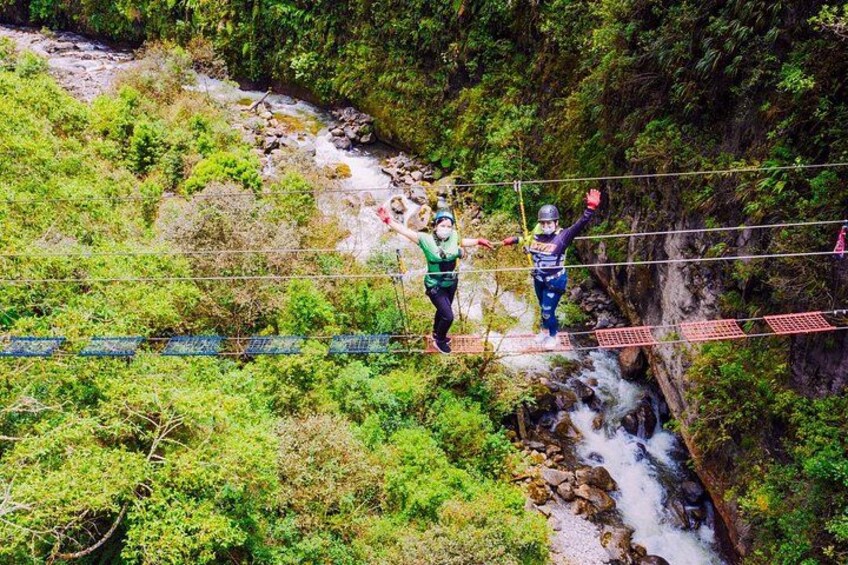 Dos personas caminando sobre un puente colgante sobre un río en un área boscosa. 3