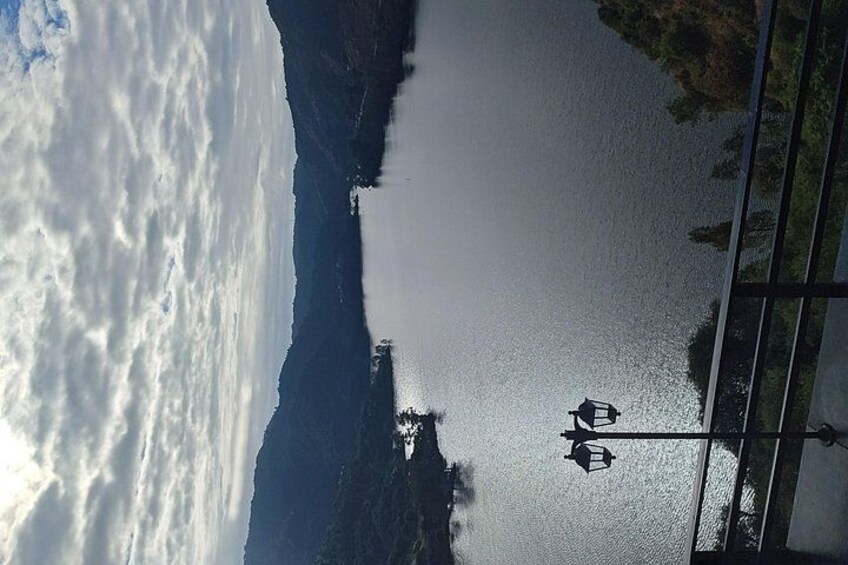 Un lago tranquilo con un bote, una cadena montañosa y un farol. 2