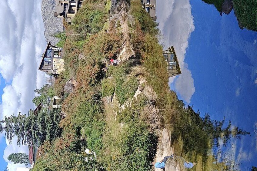 Un paisaje montañoso con cielo despejado, un río y varios edificios. 3