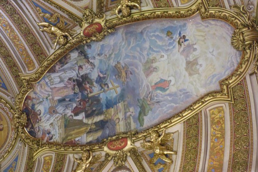 An ornate ceiling with a detailed fresco, gold accents, and intricate patterns. 2