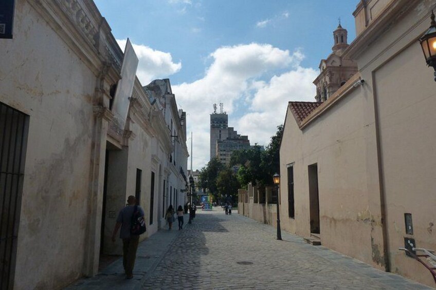 A cobblestone street flanked by historic buildings with a clear sky above. 5