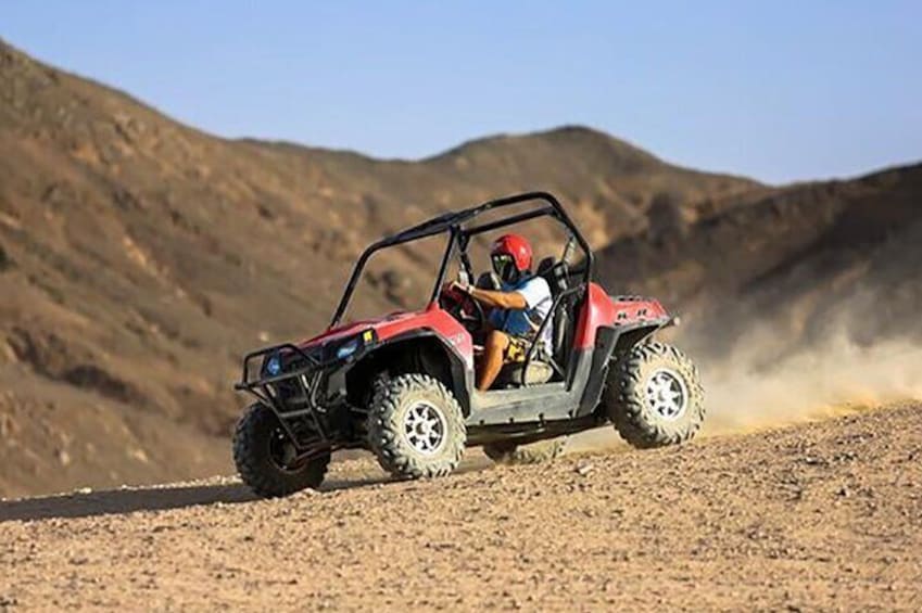 A red off-road vehicle on a dirt road with a person wearing a helmet. 5