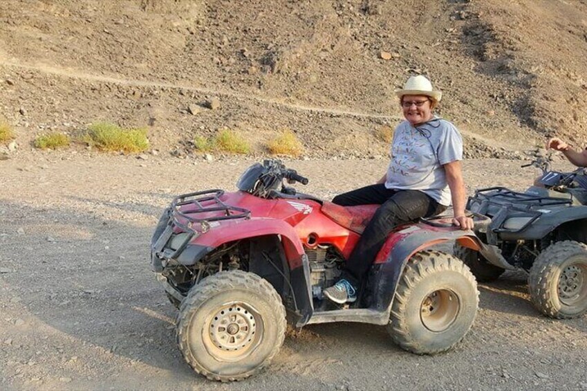 A person sitting on a red ATV in a rocky, barren landscape. 4