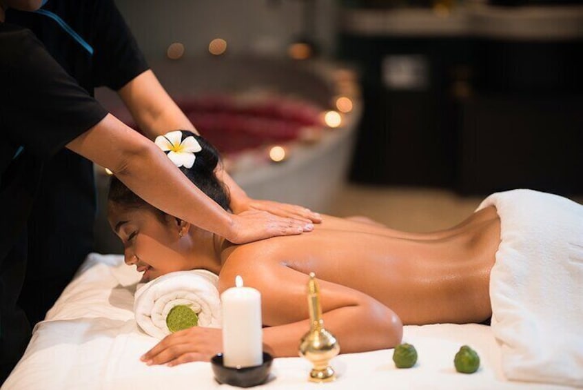 Una persona recibiendo un masaje en la espalda en un spa, con velas y una flor en el cabello. 2