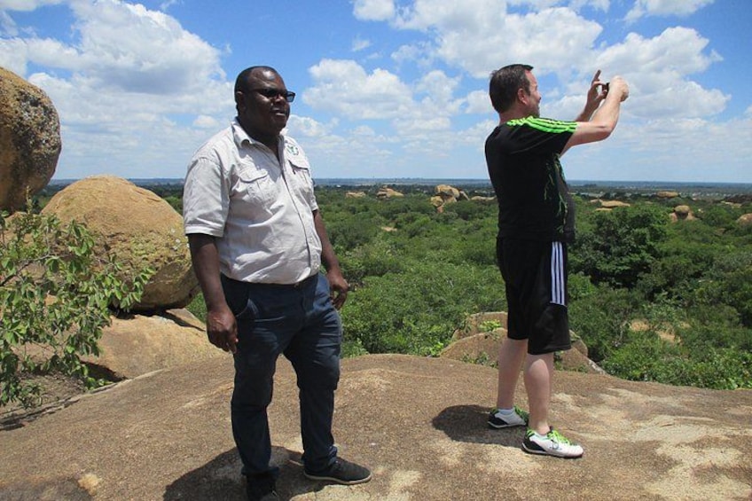 Two people standing on a rock with a view of a landscape. 3