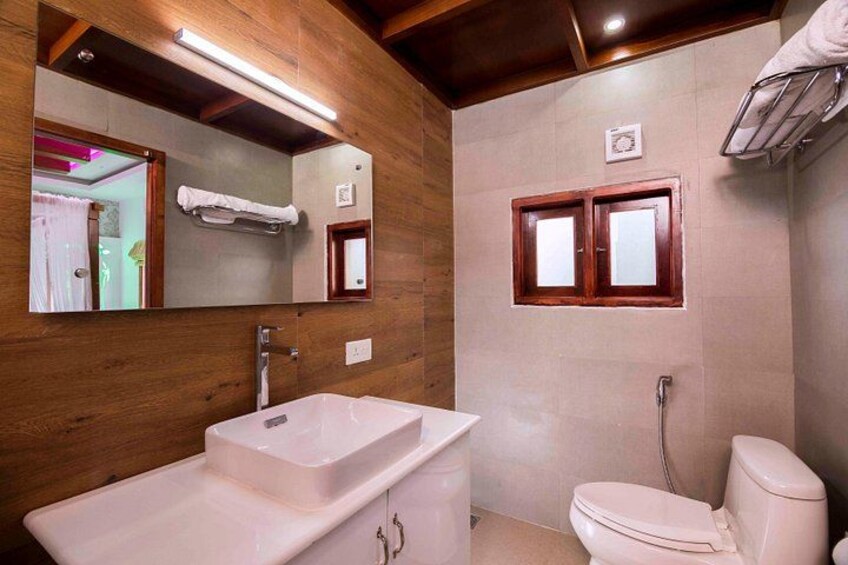 A bathroom with a wooden vanity, a white sink, a toilet, and a mirror. 2