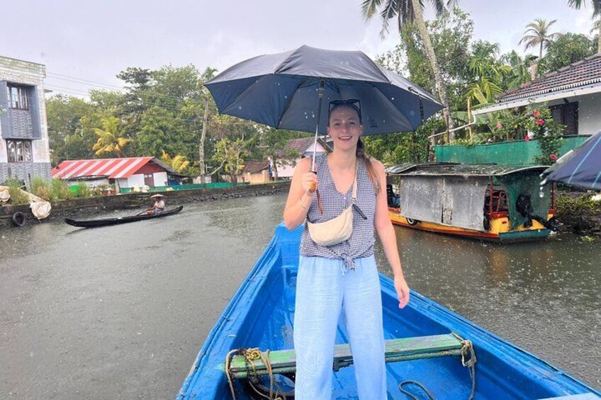 A person in a blue boat on a river, holding an umbrella. 1
