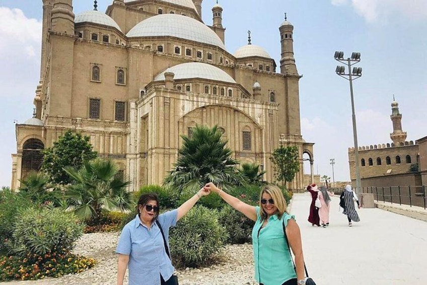 A large historic building with domes and minarets, palm trees, and a paved walkway. 5