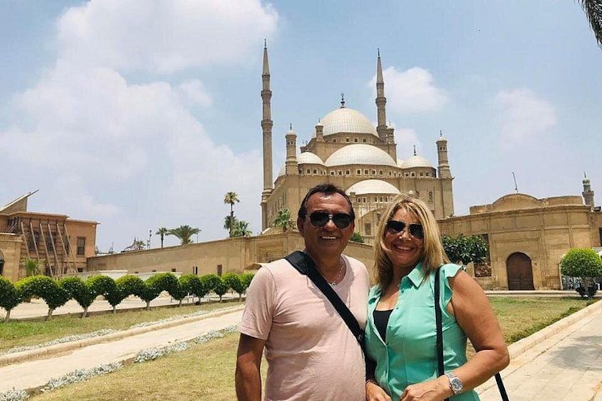 A man and a woman standing in front of a large mosque with domes and minarets. 2