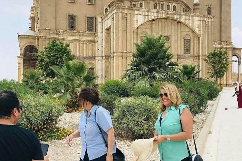 A historic building with arches and columns, palm trees, and a pathway. 3