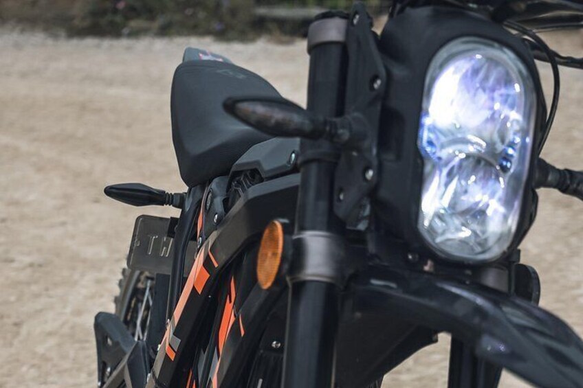 A motorcycle with a headlight, handlebars, and a rearview mirror. 3