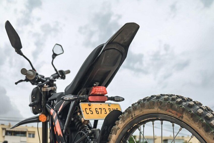 A motorcycle with a license plate, a rearview mirror, and a tire. 2