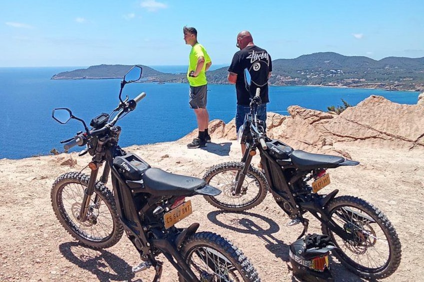 Dos motocross estacionadas sobre un terreno rocoso con vista al mar. 3