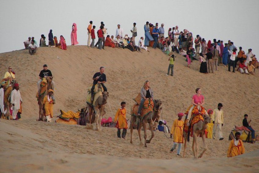 A group of people on camels in a desert setting. 3