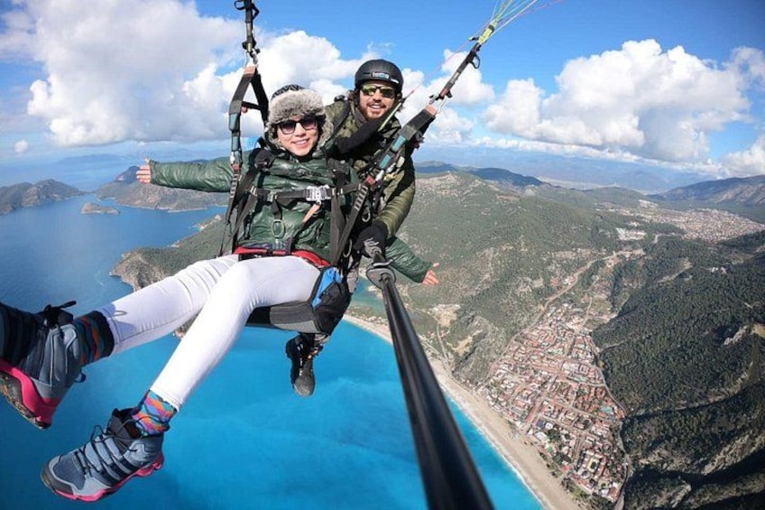 Deux personnes pratiquent le parachutisme, avec un paysage côtier en contrebas. 3