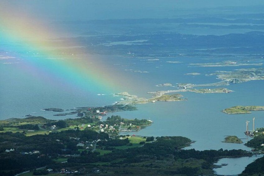 A coastal landscape with a rainbow, houses, and a bridge. 1