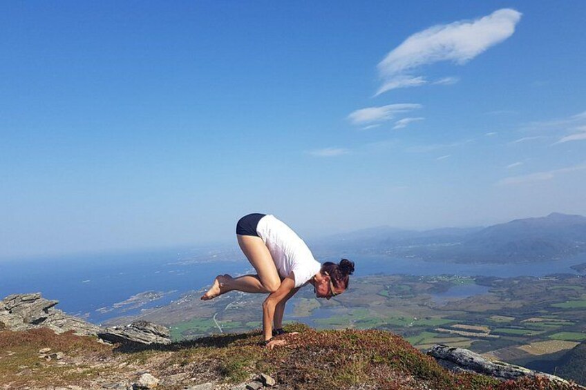 A person performing a yoga pose on a mountain peak with a scenic view of the landscape and distant mountains. 2