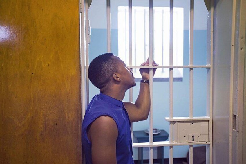 A person in a blue shirt standing in a room with barred windows and a white table. 5