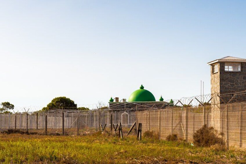 A fenced area with a green dome structure, a watchtower, and a stone building. 3