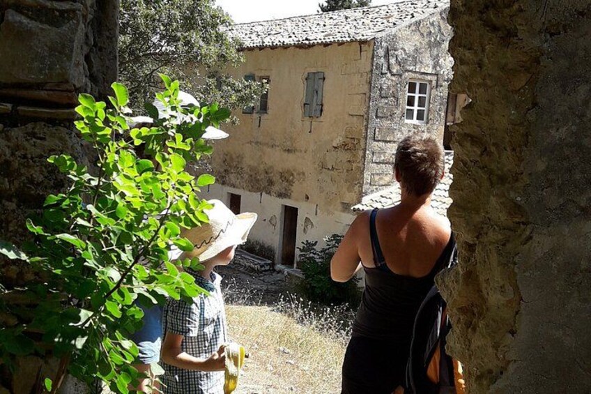 A person in a black dress and a child in a hat and checkered shirt standing in a courtyard with a building in the background. 1