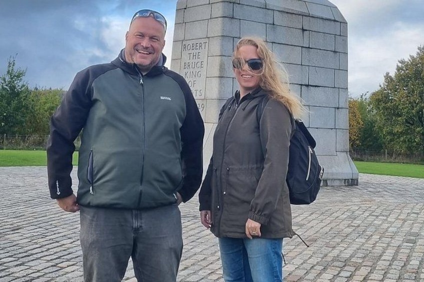 Deux personnes se tiennent devant un monument orné d’inscriptions. 5