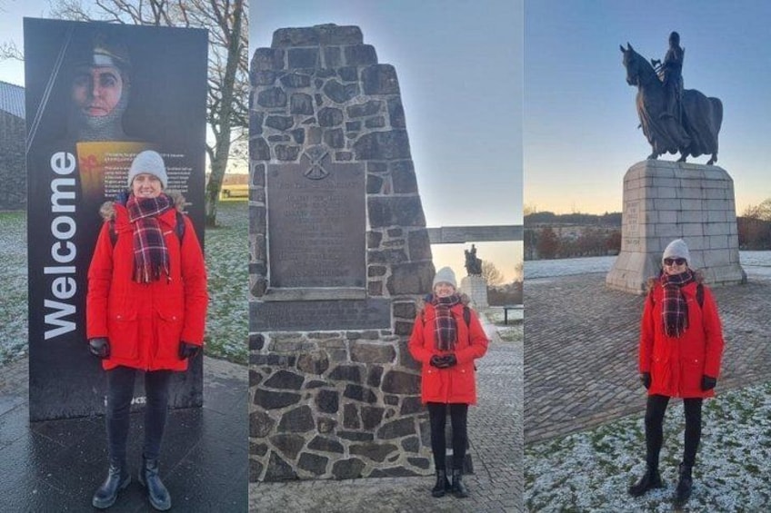 Une personne vêtue d’un manteau rouge, debout devant un monument de pierre et une statue. 3