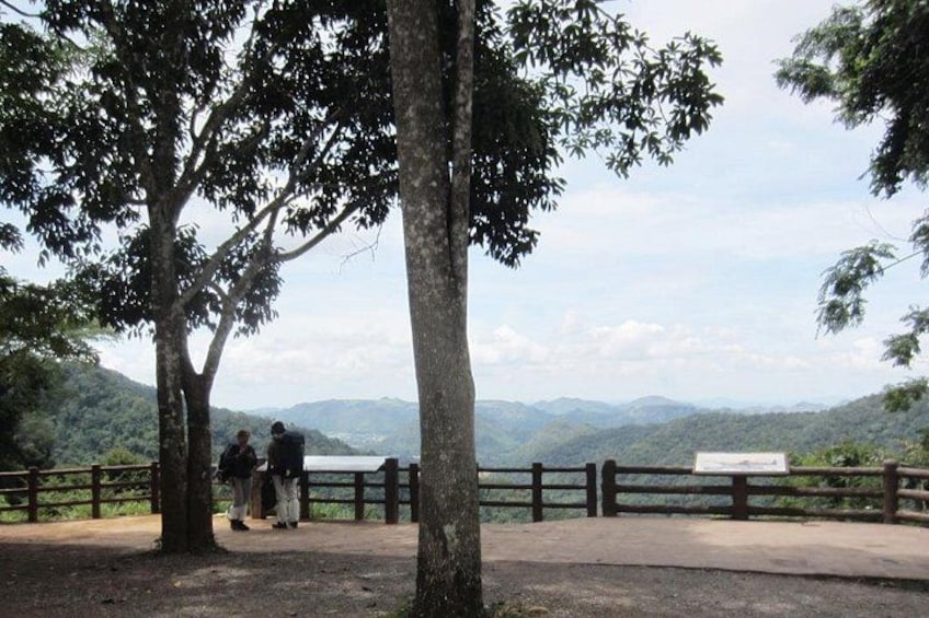 A park with a wooden fence, a bench, and a view of distant mountains. 3