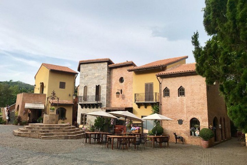 A courtyard with outdoor seating, a stone staircase, and a building with a tiled roof. 2