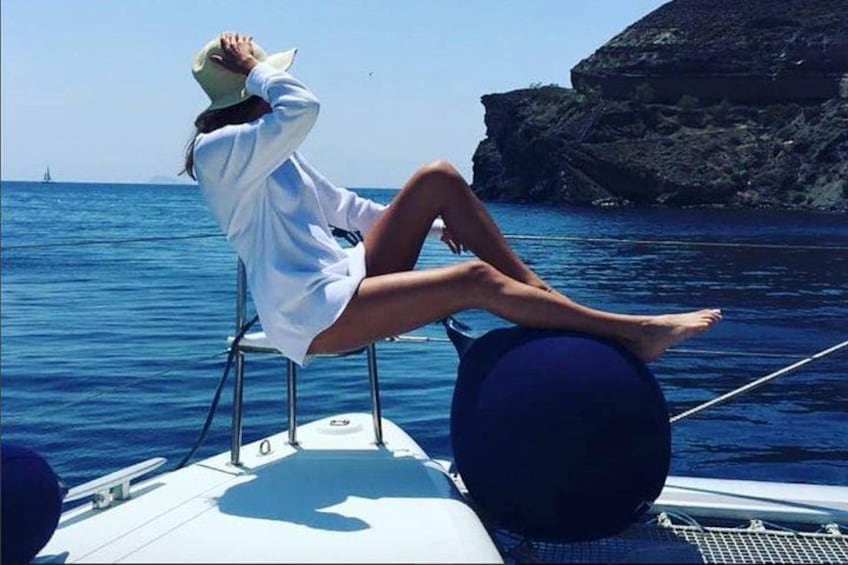 A person sitting on a chair on a boat, with the sea and a rocky coastline in the background. 5
