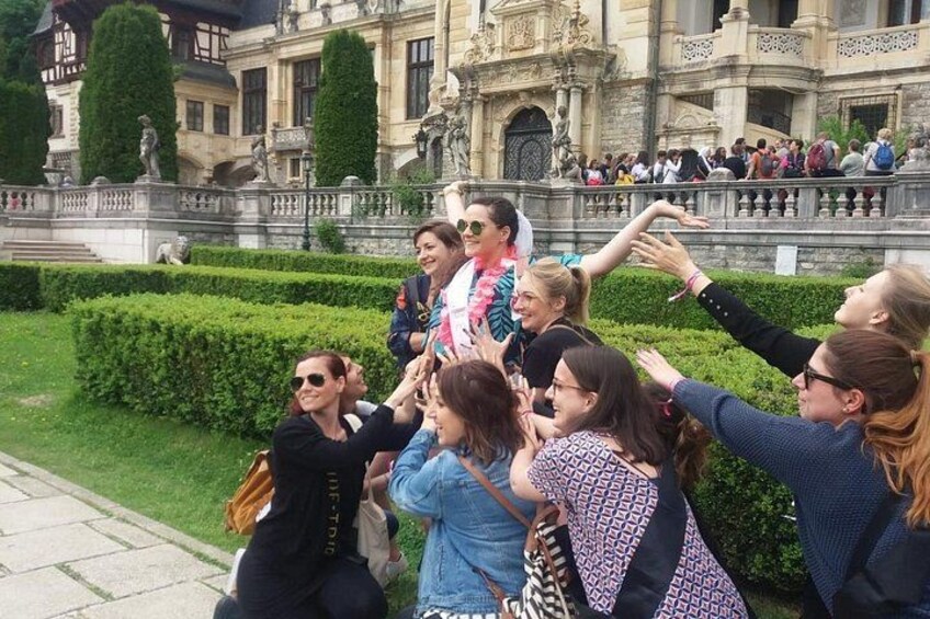 A group of people gathered in a formal garden with manicured hedges and classical architecture. 5