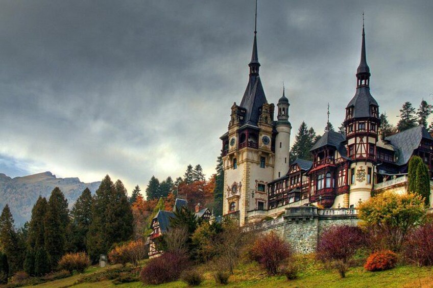 A castle with multiple towers, surrounded by autumn-colored trees and a mountainous backdrop. 3