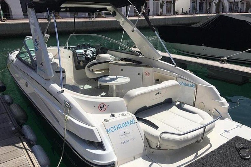 Un barco a motor blanco con la marca 'NODRAMAS' amarrado en un puerto deportivo. 1