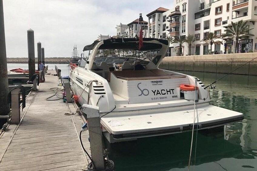 Un yate blanco amarrado en un muelle, con un paisaje urbano al fondo. 4