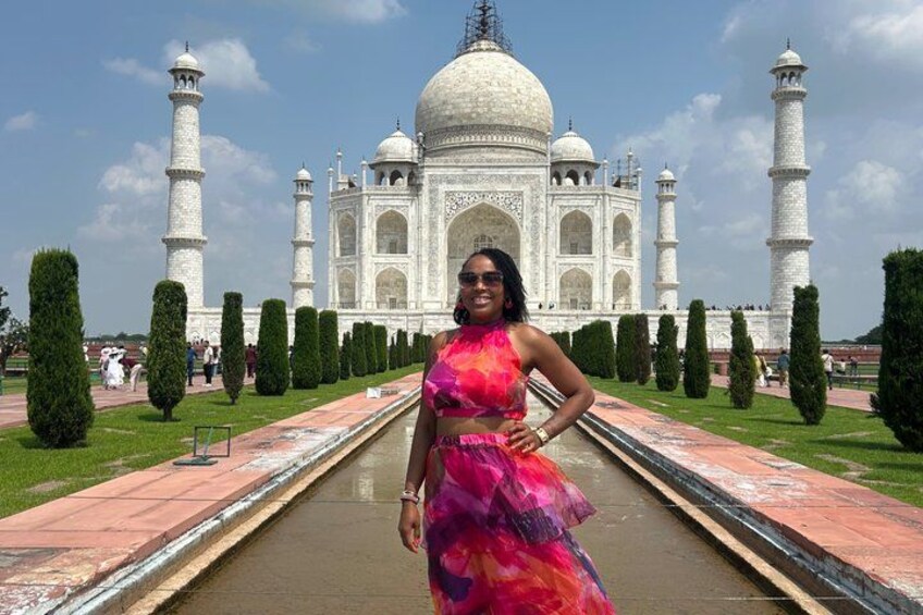 A person in a colorful dress standing in front of the Taj Mahal. 1