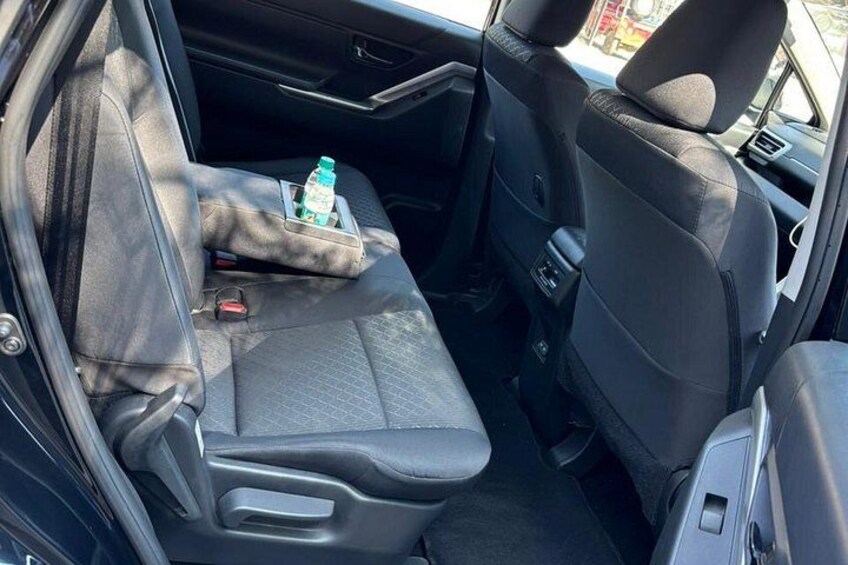 A car's interior with a rear seat, a cup holder, and a bottle of water. 3