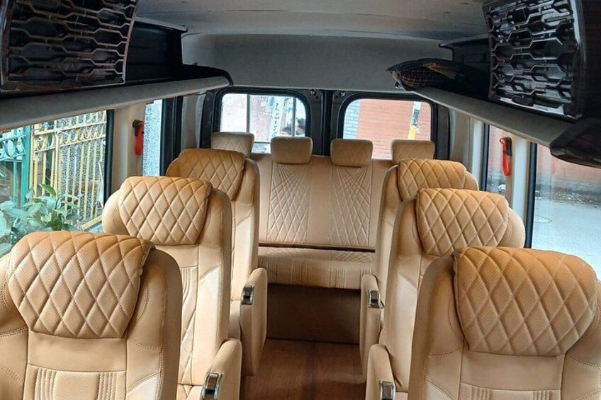 A vehicle interior with beige quilted seats and a central aisle. 5