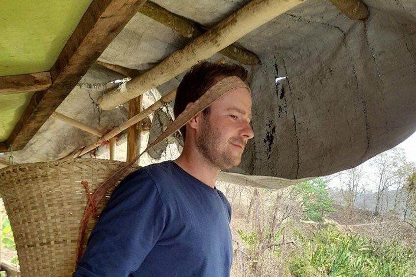 A person standing under a wooden structure with a woven basket. 4