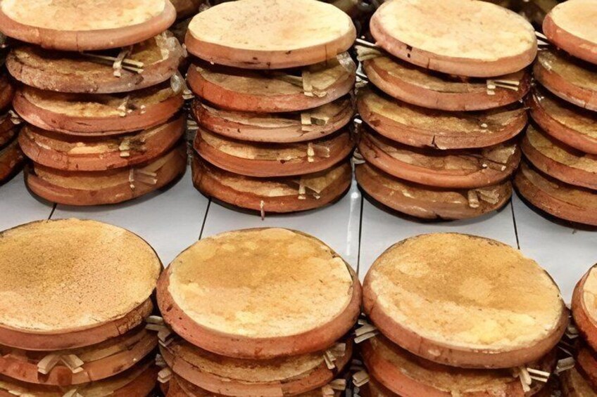 Des piles d’objets ronds et plats, de couleur brunâtre, peut-être en bois ou en métal, disposées en rangées. 2